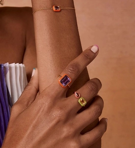 Close-up of model wearing geometric silver rings with orange, purple, and yellow zircons
