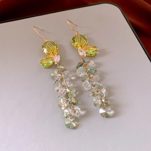Detail of green butterfly tassel earrings with iridescent crystal beads on leather