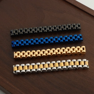 Titanium steel link bracelets in black, blue, and gold finishes on a wooden tray