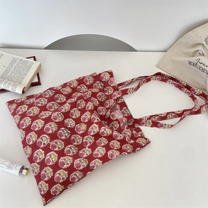 Detail of red floral canvas tote bag featuring small pink flowers and side label