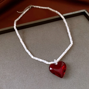 Close-up of translucent red heart pendant and white pearlescent beaded choker chain
