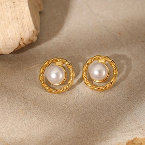 Elegant stainless steel twisted gold earrings with round pearls on stone background