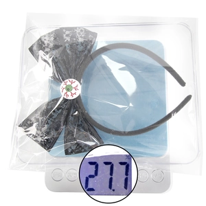 Halloween black lace bow headband with realistic green eyeball on a digital scale weighing 27.7g