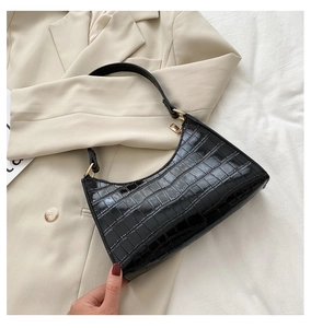 Detail view of black crocodile pattern faux leather texture on crescent underarm bag