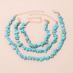 Three-piece turquoise stone necklace set with golden chains on pink texture