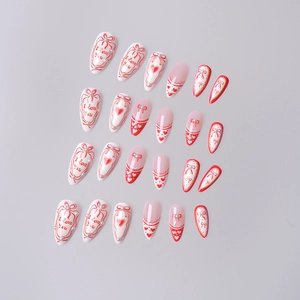Close-up of almond French press-on nails with red bows, pearls, and I love you text