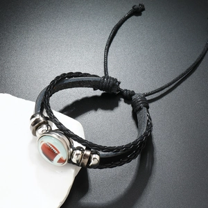 Détail du bracelet réglable en cuir noir tressé avec un charme dôme en verre football