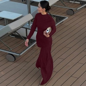 Detail of burgundy slim fit dress featuring ruched fabric and asymmetric hem design
