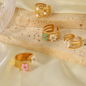 Detailed macro of gold plated stainless steel pearl rings with colorful bead flowers