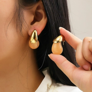 Detail of 18k gold plated drop earrings with translucent pink resin stones on ear