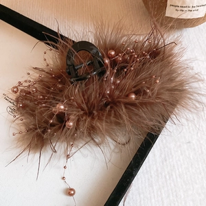 Detail of brown feather hair claw clip with rose gold glass pearls and elegant texture