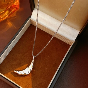 Detailed view of the 18k gold plated croissant pendant on dark velvet display