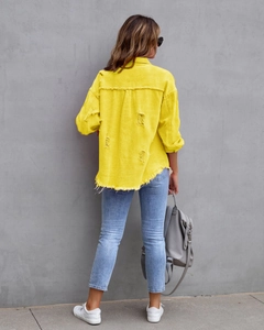 Detail der gelben Jeansjacke mit ausgefransten Kanten und Rissen am Rückenbereich