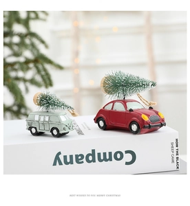 Close-up of red and teal vintage toy cars with snow-dusted Christmas trees on top