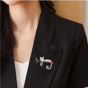 Cute white polka dot cat brooch with green leaves on a black suit lapel