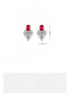 Detail view of peacock feather earrings with red gemstones and sparkling white zircons