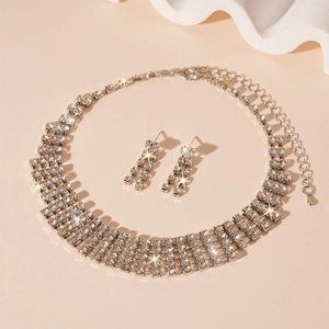 Detailed view of silver necklace and fringe earrings set with sparkling rhinestones