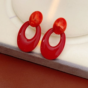 Macro shot of glossy red oval earrings featuring a polished texture and stud closure