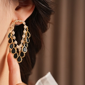 Detail shot of gold tassel earrings with black teardrop stones and shimmering zircons