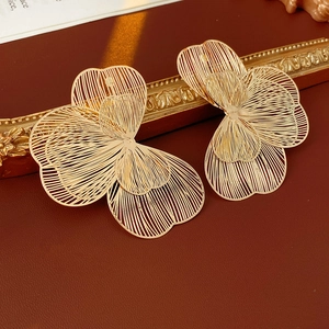 Détail de boucles d'oreilles fleurs dorées ajourées avec textures de pétales