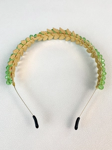 Close-up of golden leaf metal headband decorated with vibrant green faceted beads