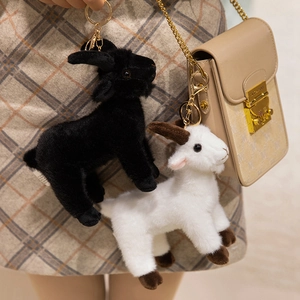 Cute black and white plush goat pendants on a beige leather bag with golden keychains
