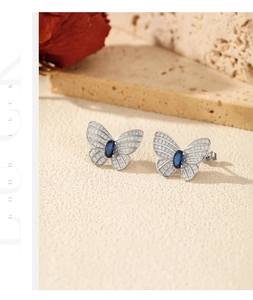 Gros plan de boucles d'oreilles papillon en argent avec gemme bleue et diamants