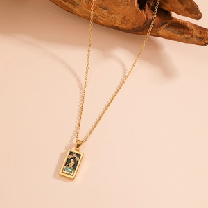 Macro shot of vintage rectangular tarot pendant with black enamel and blue gems on gold chain