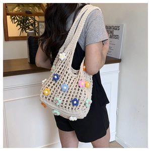 Detailed close-up of cream knit tote bag with colorful hand-crocheted floral decorations