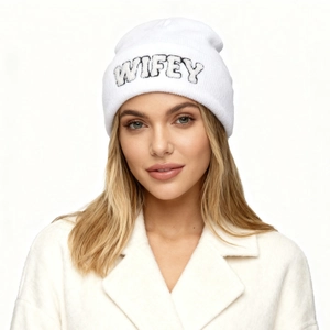 Gros plan sur un bonnet en tricot blanc avec broderie WIFEY et texture douce d'hiver