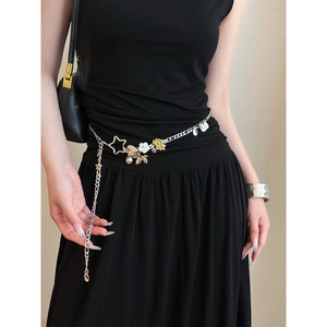 Detail of silver double-layered waist chain with star and shell pendants on black dress