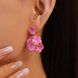 Gros plan de boucles d'oreilles fleurs roses à bordure dorée portées par un mannequin