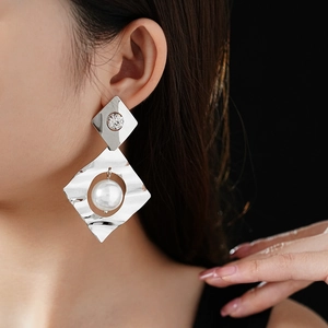 Macro view of geometric silver earrings with textured metal and white pearls