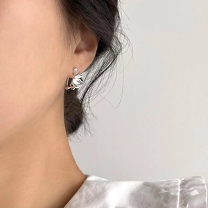 Close-up of minimalist silver floral heart stud earrings worn for elegant style