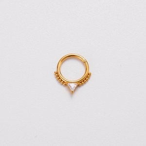 Macro shot of gold 16G stainless steel nose hoop with zircon triangle and small beads