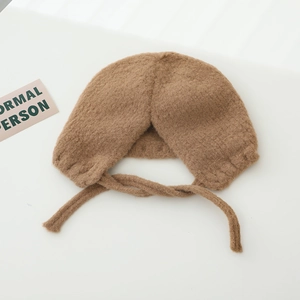Vue détaillée du bonnet en peluche marron pour bébé avec protège-oreilles et sangles