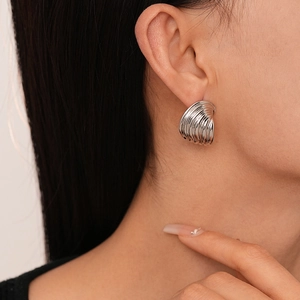 Macro shot of silver croissant earrings with shell texture on model's ear