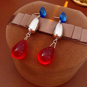 Detail view of teardrop earrings with blue rhombus studs and red resin pendants