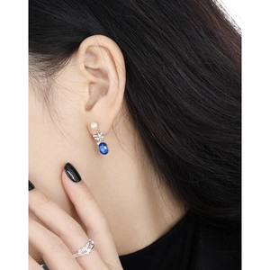 Blue gemstone drop earrings with white pearls and silver floral design on model