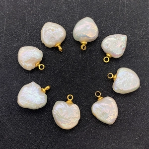 Eight heart-shaped natural freshwater pearl pendants with gold loops on black texture