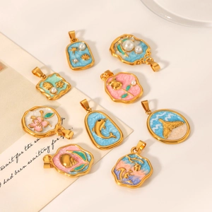 Flat lay of gold enamel ocean charms and pearl pendants on a white artistic background