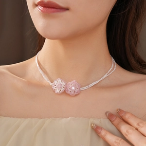 Detail of double-layer bamboo bead necklace featuring pink flower charms on model