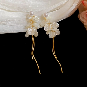 Detailed close-up of white petal tassel earrings with pearls and gold snake chains