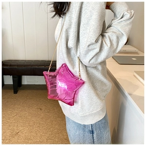 Detail of transparent star-shaped pink PVC crossbody bag with golden chain strap on model
