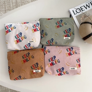 Flat lay of corduroy makeup pouches with Keep Smiling embroidery in four pastel colors