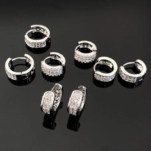 Macro view of assorted silver huggie earrings with micro-paved cubic zirconia stones