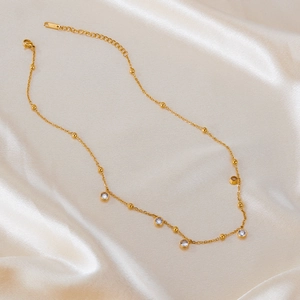 Elegant gold stainless steel necklace with round cubic zirconia bezel set on satin background