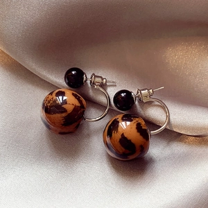 Détails de boucles d'oreilles en acrylique à motif léopard et doubles perles sur satin champagne