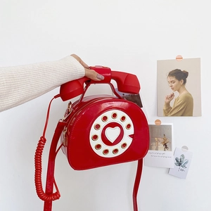 Detail of red patent leather telephone crossbody bag with heart dial and curly cord