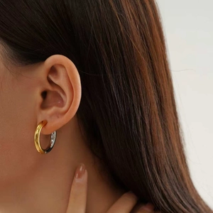 Detail shot of chunky two-tone gold and silver earrings worn by a model